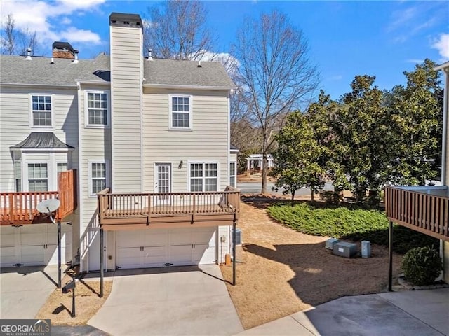 back of house with a garage, a chimney, and concrete driveway