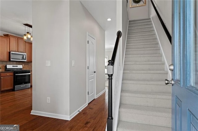 staircase with baseboards, wood finished floors, and recessed lighting