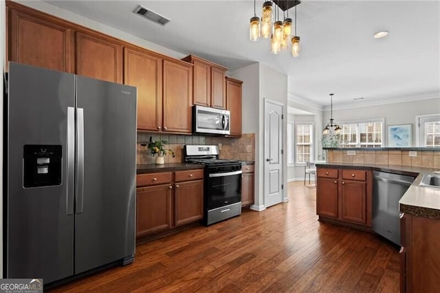 kitchen featuring tasteful backsplash, visible vents, brown cabinetry, appliances with stainless steel finishes, and a chandelier