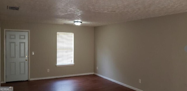 spare room with baseboards, a textured ceiling, visible vents, and wood finished floors