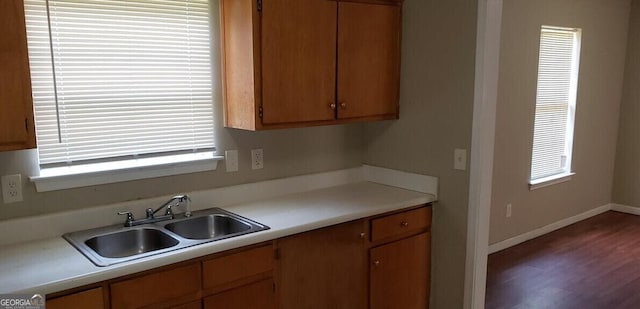 kitchen featuring baseboards, light countertops, a sink, and wood finished floors