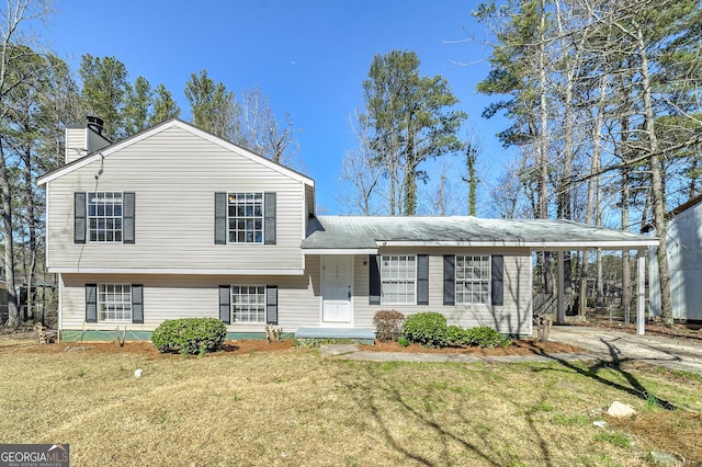 split level home featuring driveway, a chimney, and a front yard