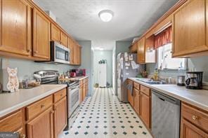 kitchen with light countertops, brown cabinetry, and stainless steel appliances