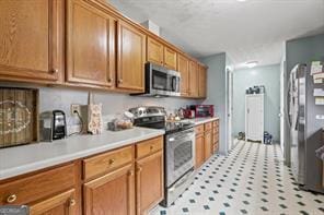 kitchen with brown cabinets, appliances with stainless steel finishes, and light countertops