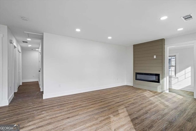 unfurnished living room with recessed lighting, a large fireplace, visible vents, and wood finished floors