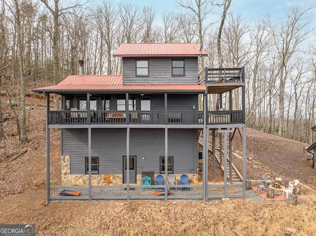 view of front of home featuring a balcony, metal roof, and a patio