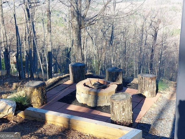 exterior space with a fire pit and a wooded view