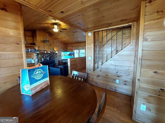 dining room featuring a ceiling fan, wood ceiling, wood-type flooring, vaulted ceiling, and wood walls