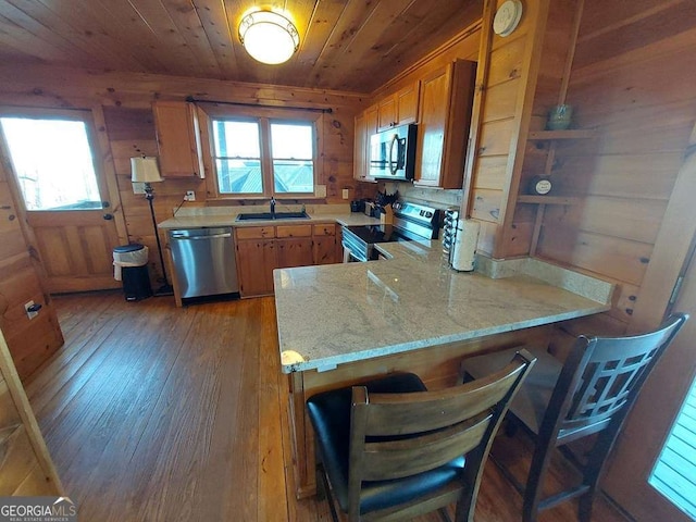 kitchen featuring wooden ceiling, stainless steel appliances, a peninsula, wood walls, and light wood-type flooring