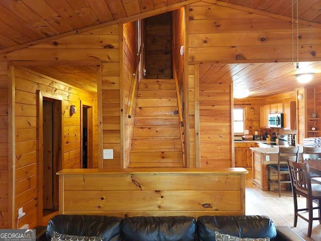 living area featuring lofted ceiling, wood walls, and wood ceiling