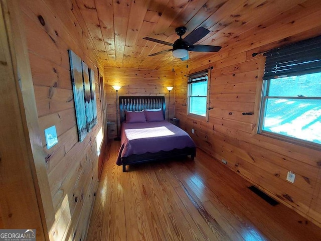 unfurnished bedroom featuring wood ceiling, visible vents, wood-type flooring, and wooden walls