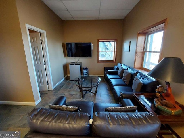 living area featuring baseboards, a drop ceiling, and tile patterned floors