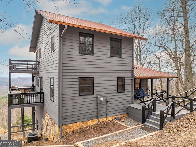 view of side of home featuring metal roof and central air condition unit