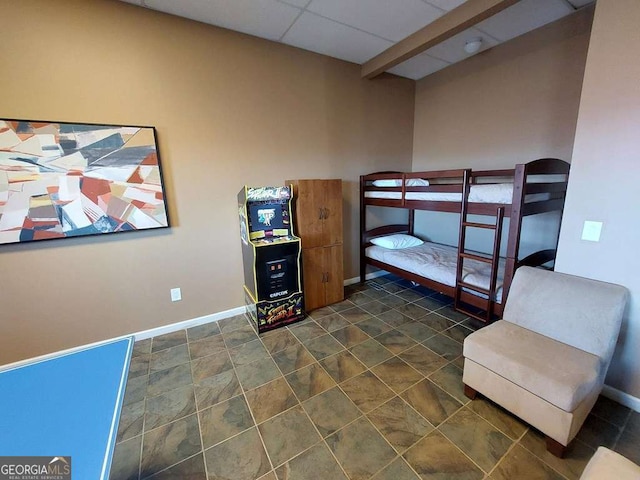 bedroom with a drop ceiling and baseboards