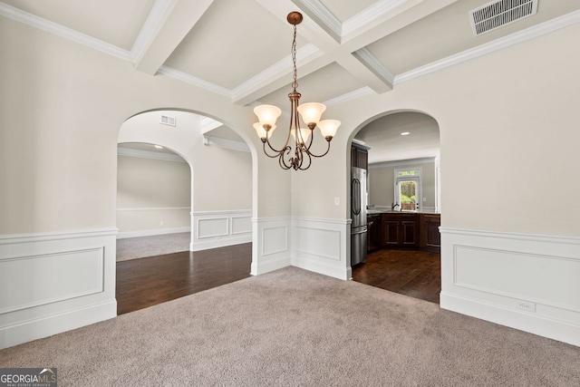 empty room with visible vents, coffered ceiling, a wainscoted wall, dark carpet, and beam ceiling