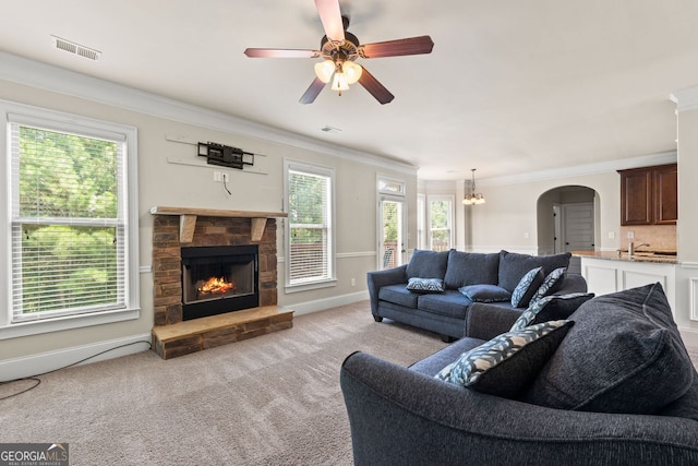 living area with ornamental molding, arched walkways, and plenty of natural light