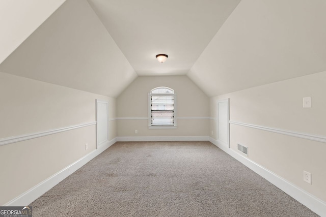 bonus room with vaulted ceiling, baseboards, visible vents, and light colored carpet