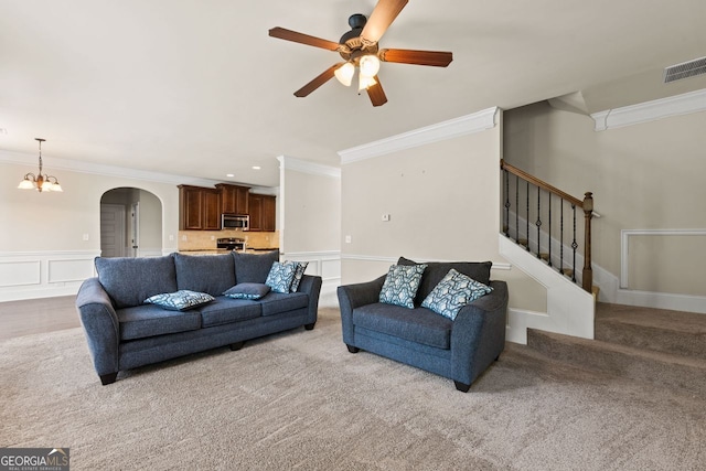 living room with arched walkways, visible vents, crown molding, and stairway