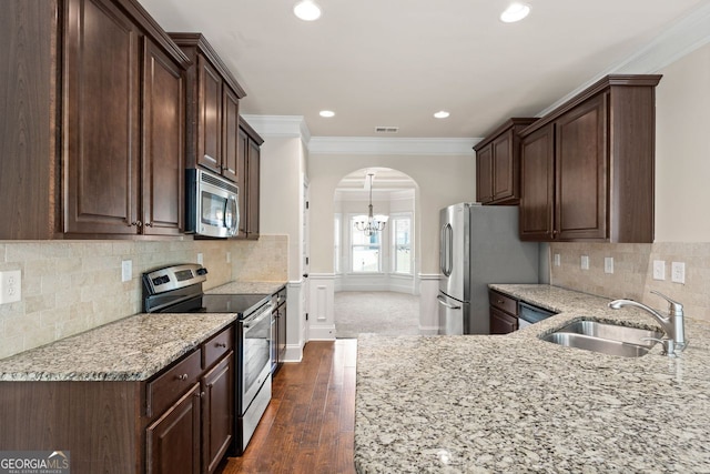 kitchen featuring arched walkways, visible vents, appliances with stainless steel finishes, ornamental molding, and a sink