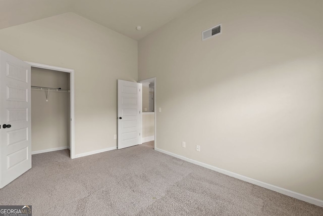 unfurnished bedroom with carpet floors, a closet, visible vents, high vaulted ceiling, and baseboards