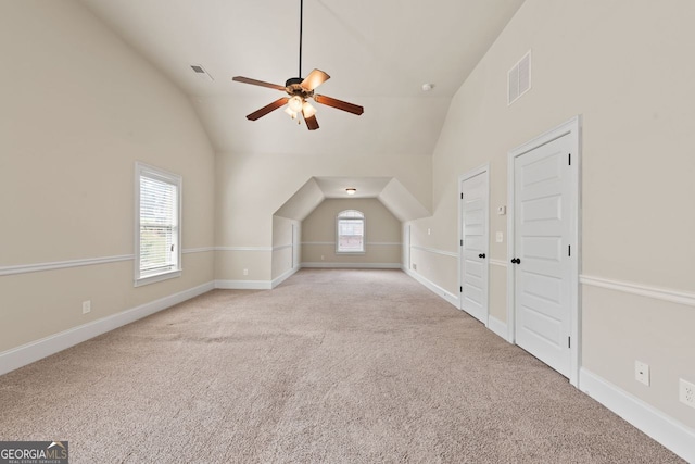 additional living space featuring lofted ceiling, baseboards, visible vents, and light colored carpet