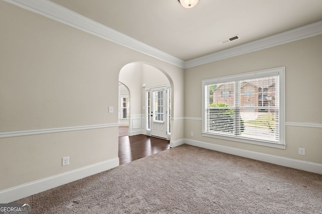 carpeted spare room with arched walkways, visible vents, crown molding, and baseboards