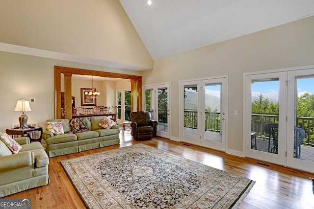 living room featuring an inviting chandelier, visible vents, high vaulted ceiling, and wood finished floors