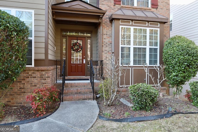 doorway to property with brick siding and a standing seam roof