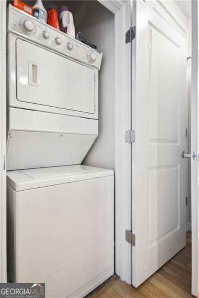 laundry area with light wood-type flooring, stacked washer / drying machine, and laundry area