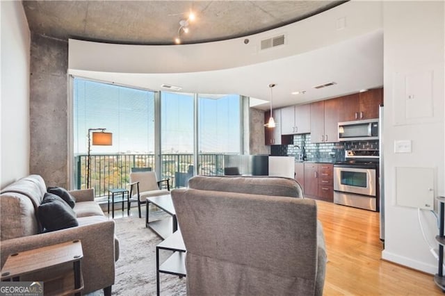 living area featuring light wood finished floors, visible vents, and floor to ceiling windows