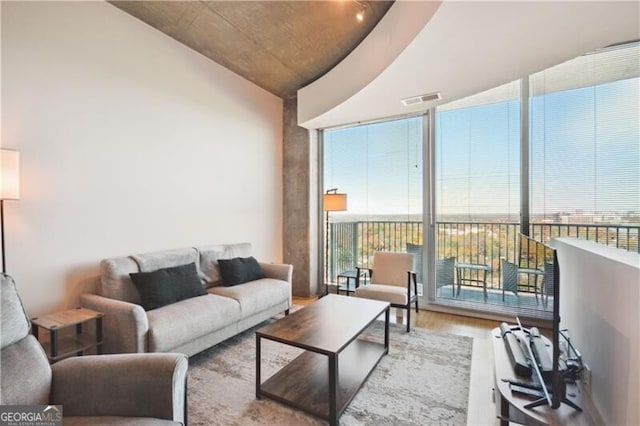 living area with a wall of windows, wood finished floors, and visible vents