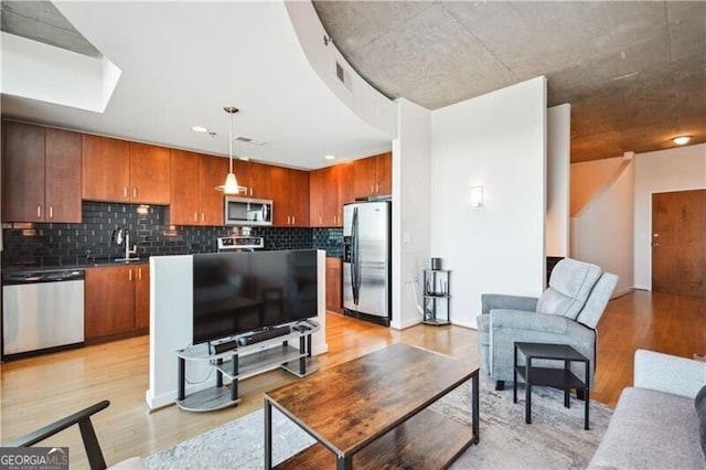 living room with a skylight, visible vents, and light wood-style flooring