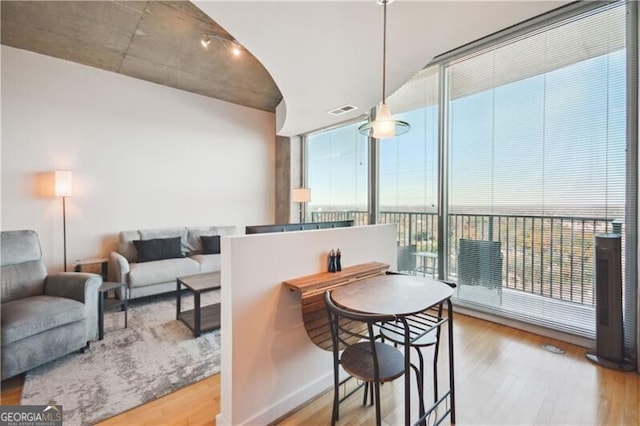 dining area with expansive windows, visible vents, and wood finished floors