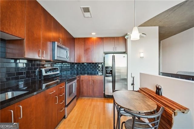 kitchen featuring tasteful backsplash, visible vents, appliances with stainless steel finishes, dark stone countertops, and light wood-type flooring