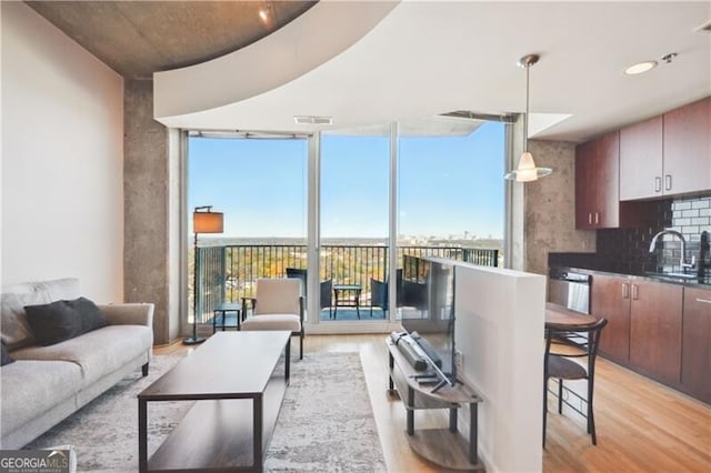 living area with light wood-style flooring, visible vents, and a wall of windows