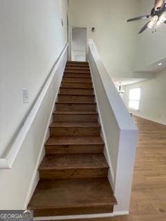 stairs with a ceiling fan and wood finished floors