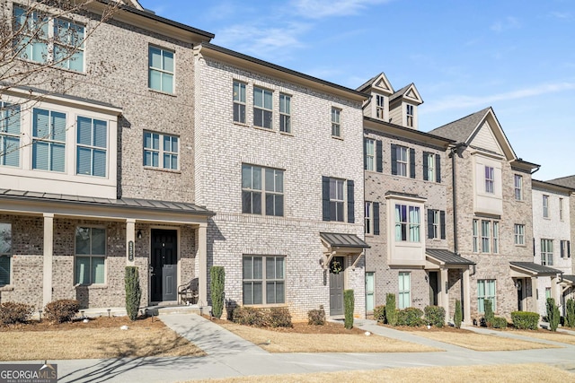 multi unit property featuring a standing seam roof, metal roof, and brick siding