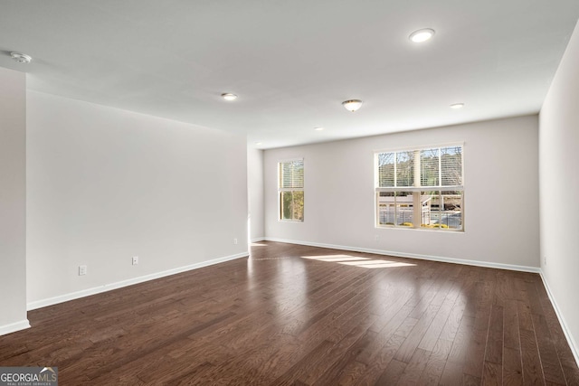 spare room with baseboards, dark wood finished floors, and recessed lighting