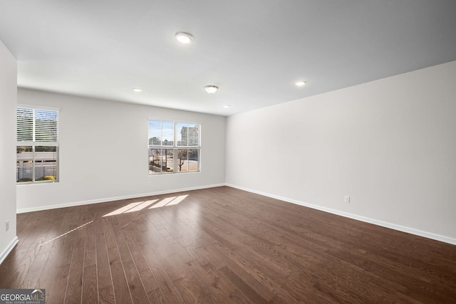 spare room featuring baseboards and dark wood finished floors