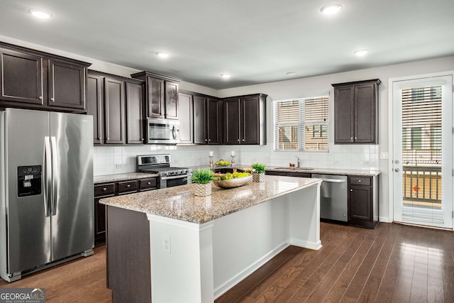 kitchen with dark wood-style floors, stainless steel appliances, a sink, and light stone countertops