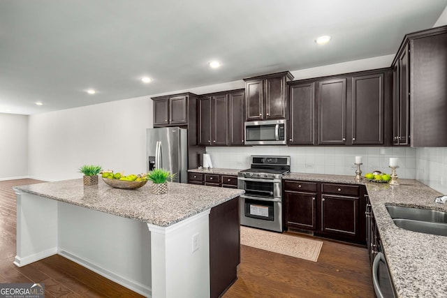 kitchen with stainless steel appliances, a kitchen island, a sink, and dark wood-style floors