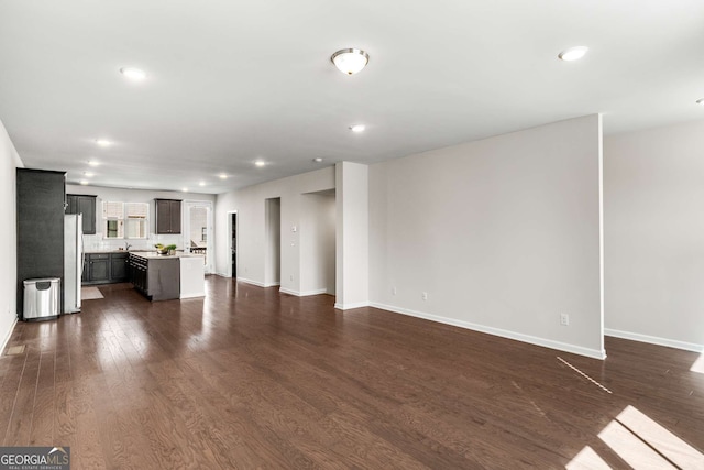 unfurnished living room featuring dark wood-style flooring, recessed lighting, and baseboards