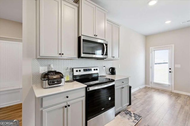 kitchen featuring appliances with stainless steel finishes, light wood-type flooring, visible vents, and tasteful backsplash