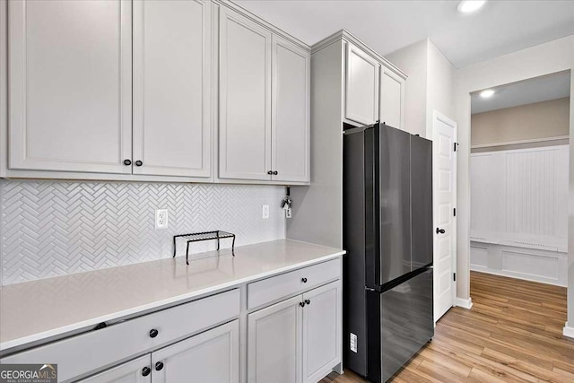 kitchen with tasteful backsplash, freestanding refrigerator, light countertops, light wood-type flooring, and recessed lighting