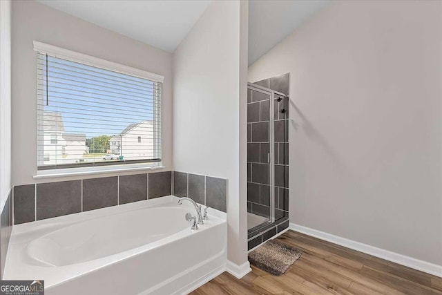 full bathroom with a stall shower, wood finished floors, baseboards, and a bath