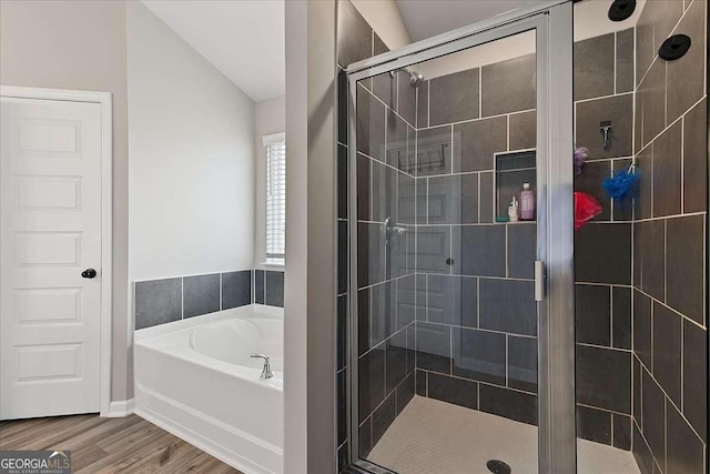 full bath featuring lofted ceiling, wood finished floors, a shower stall, and a bath