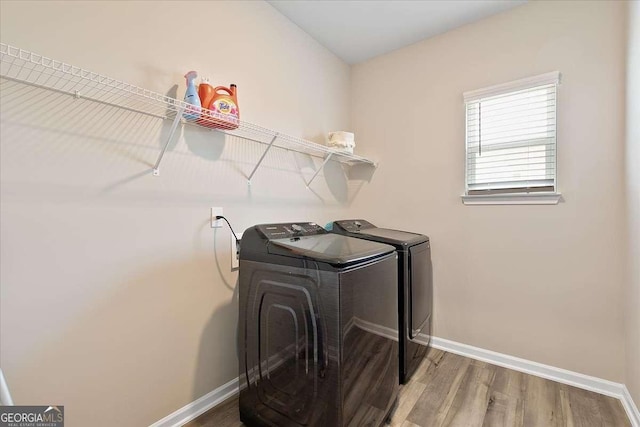 laundry room with laundry area, independent washer and dryer, wood finished floors, and baseboards