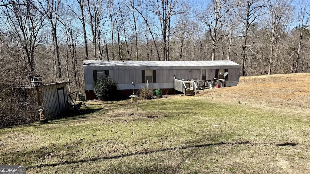 manufactured / mobile home with a view of trees and a front lawn