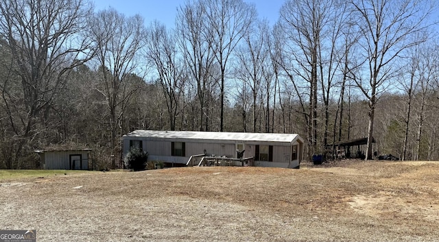 view of front of home featuring an outdoor structure and a wooded view