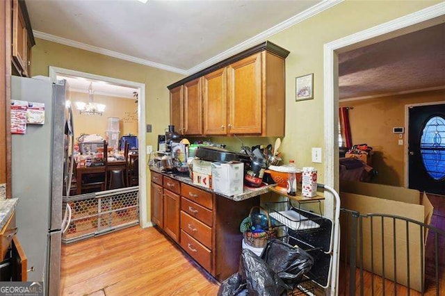 kitchen featuring light wood-style floors, freestanding refrigerator, brown cabinetry, an inviting chandelier, and crown molding